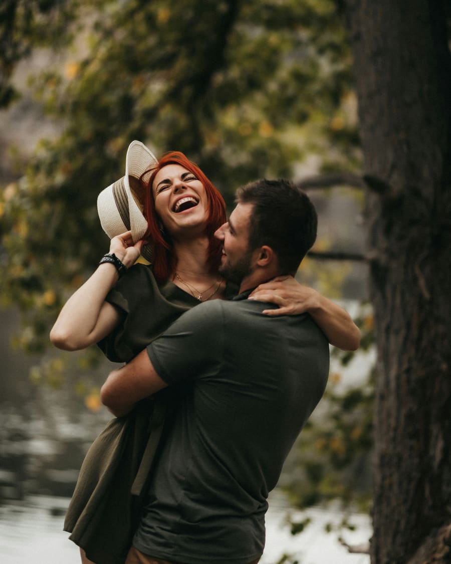 A woman laughing beside a warm male companion in an easy social moment.