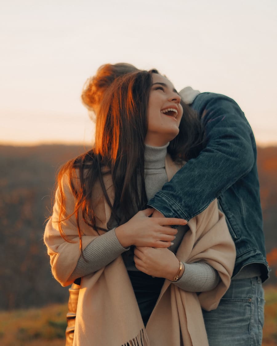 A woman laughing beside a warm male companion in an easy social moment.