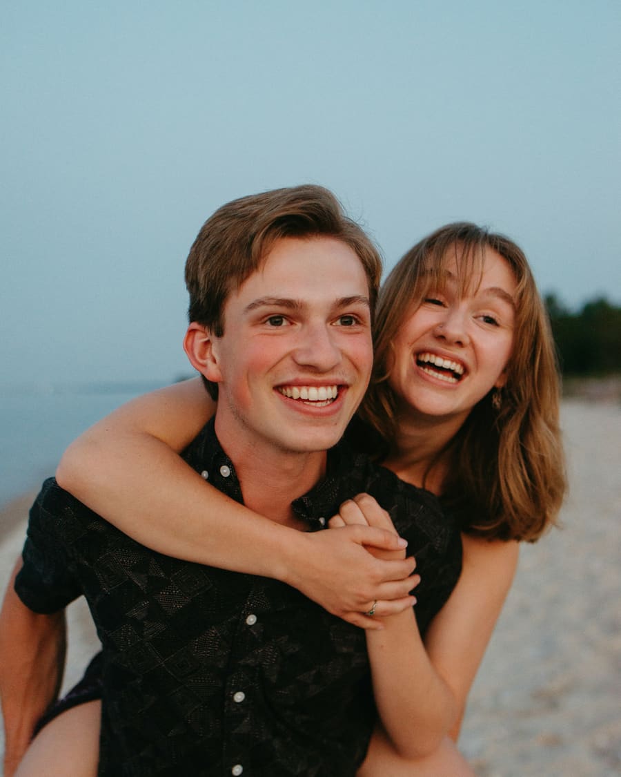 A woman smiling with her companion in bright coastal light.